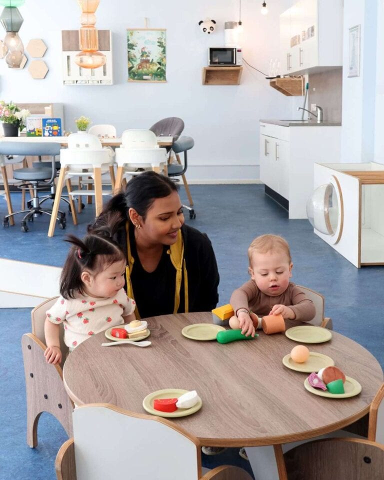 Medewerkster kinderopvang met kinderen aan tafel